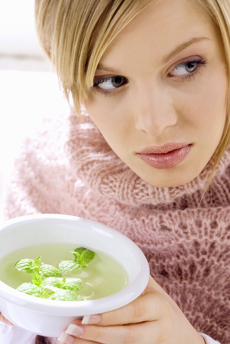 Young woman holding bowl of peppermint tea
