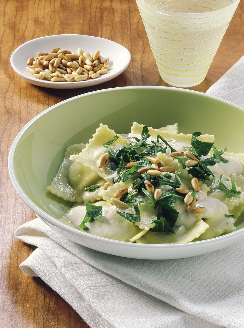 Ravioli in herb cheese sauce with rocket and pine nuts