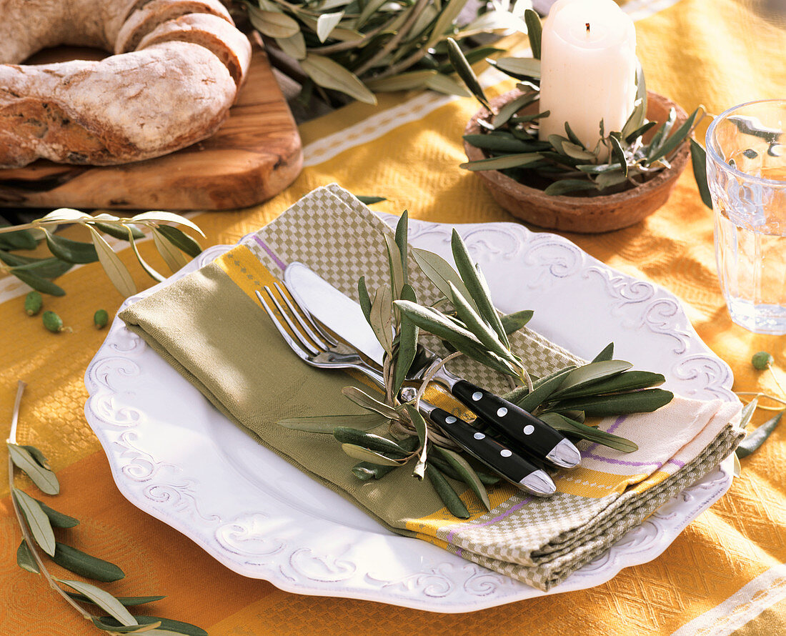 Gedeckter Tisch mit Olivenblättern dekoriert