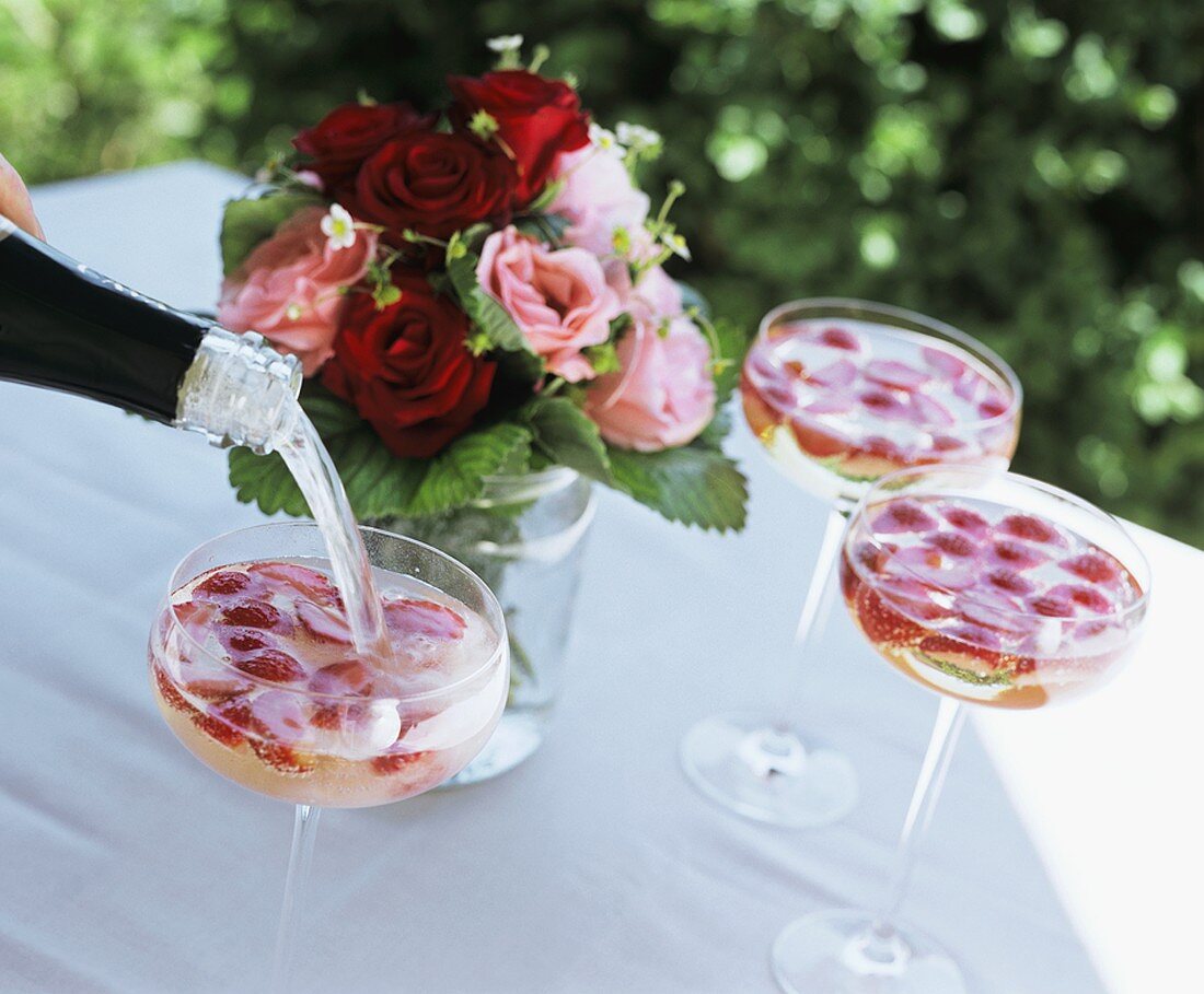 Sekt (sparkling wine) being poured into a glass of strawberries