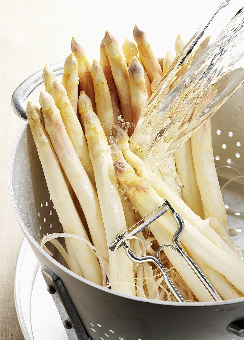 White asparagus spears being washed in colander