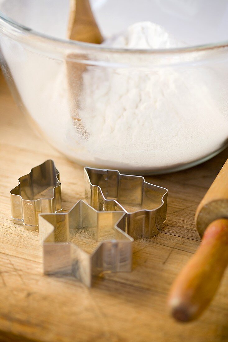 A bowl of flour with biscuit cutters