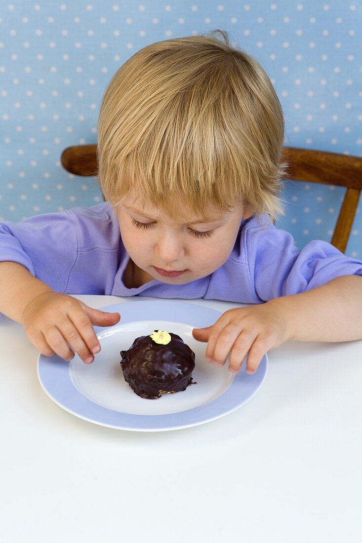 Small boy looking at a small chocolate cake