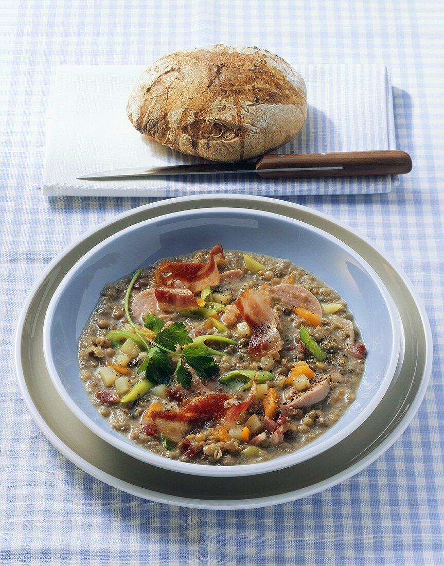 Linsensuppe mit Speck, Wurst und kleinem Brotlaib