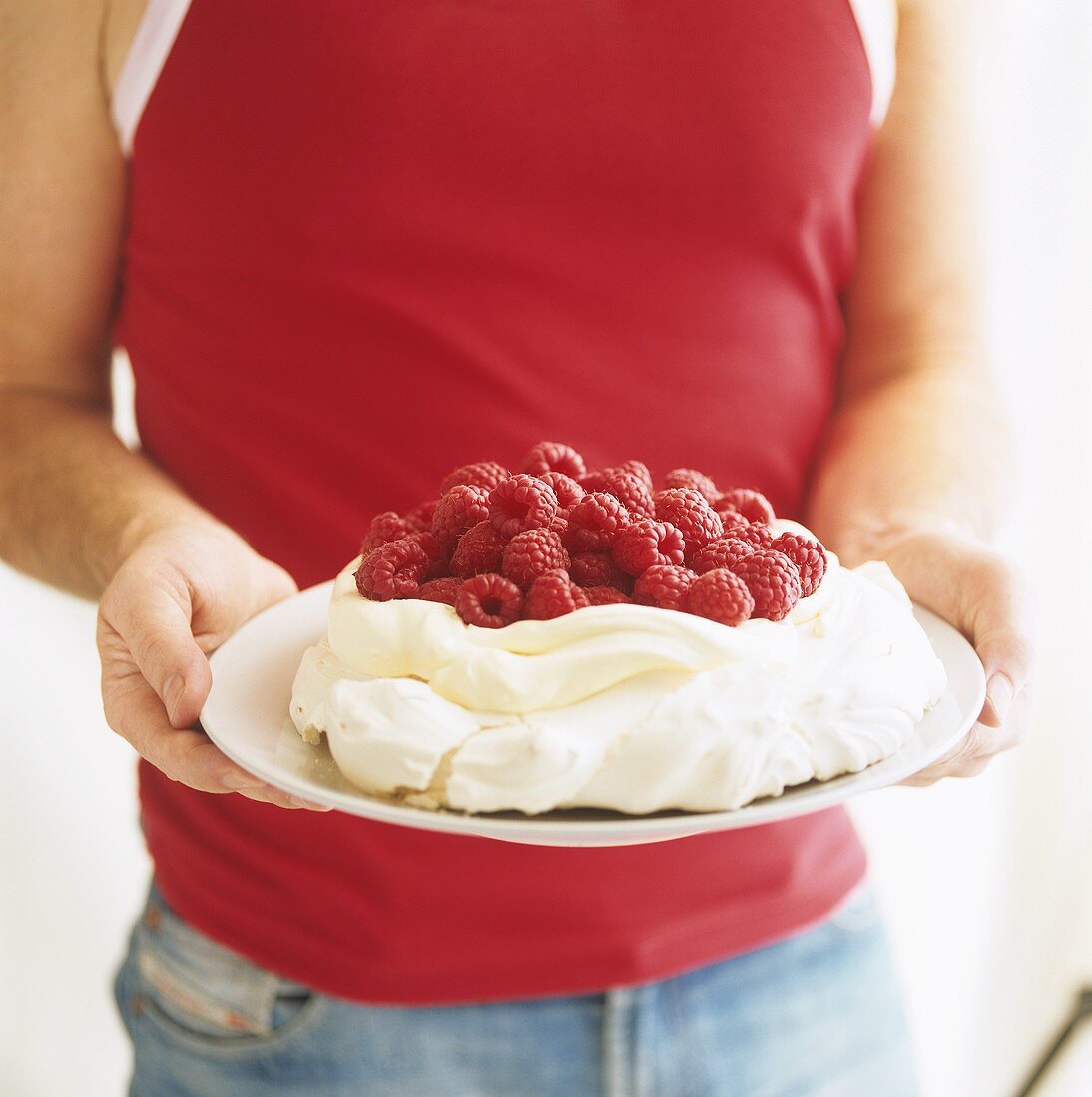 Mann hält Pavlova mit Himbeeren