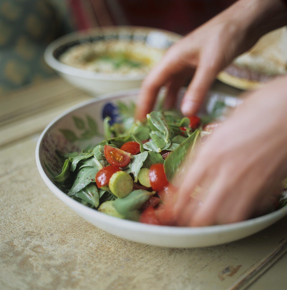 Salat wird mit Händen gemischt