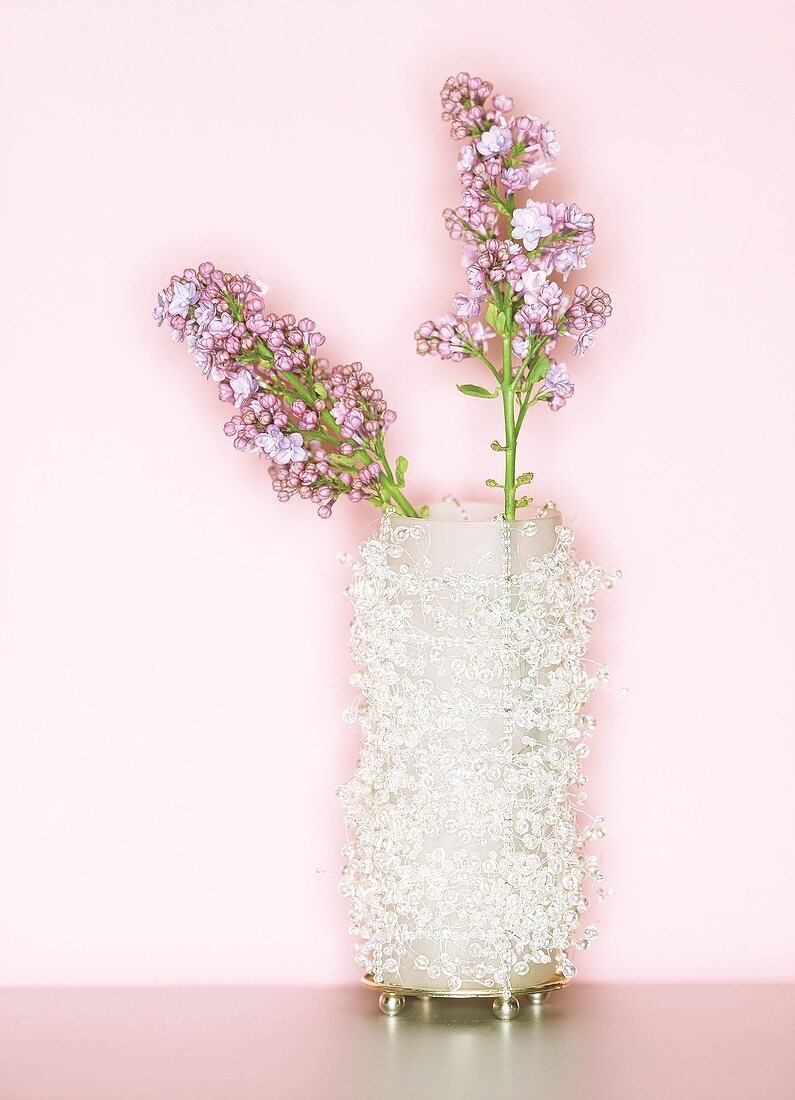 Zwei rosa Fliederblüten in einer Perlenvase