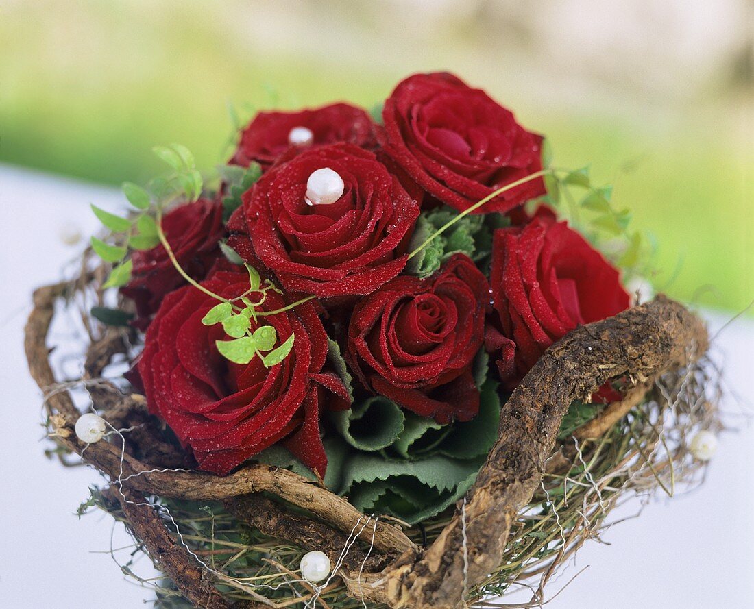 A bouquet of roses with beads surrounded by a wreath of twigs