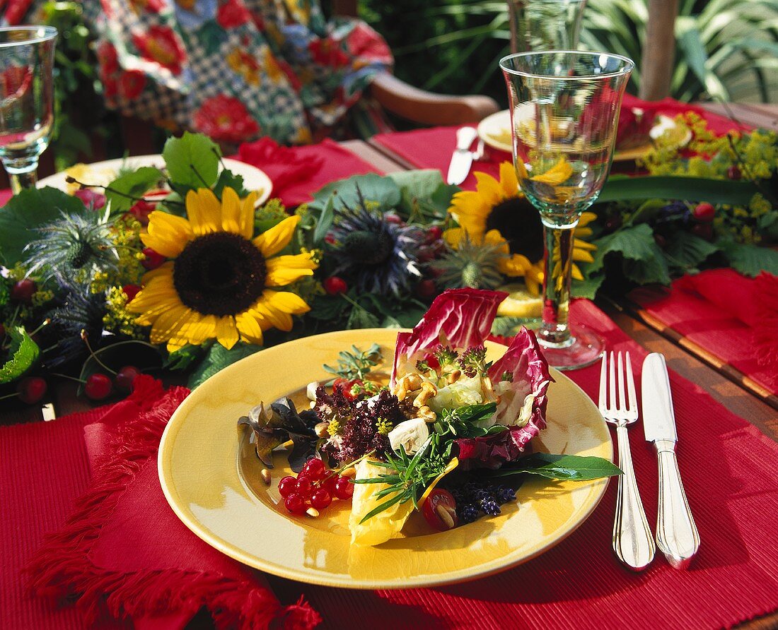 Teller mit Salat auf einem Tisch mit Blumengirlande