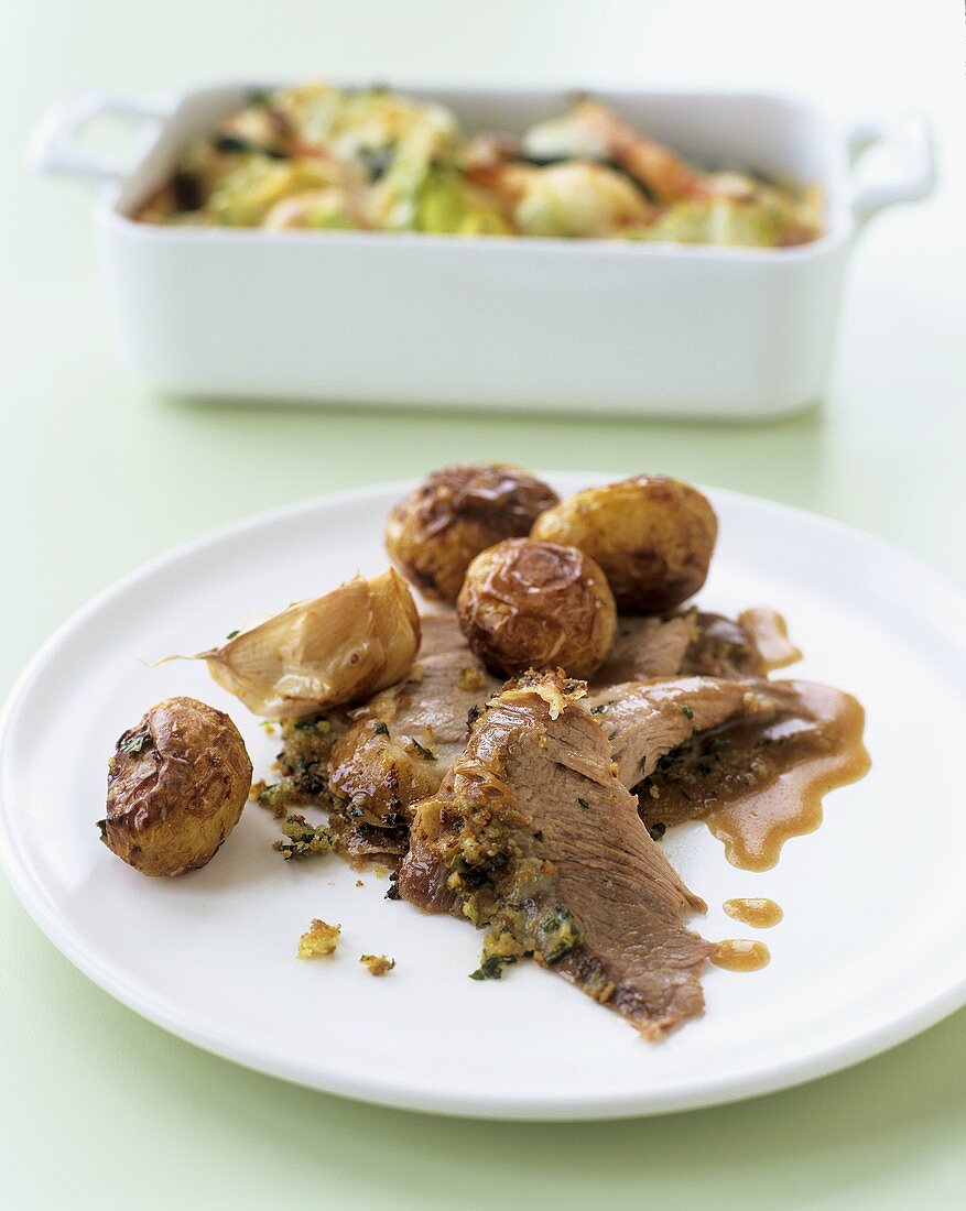 Lamb with garlic, roast potatoes and vegetable gratin