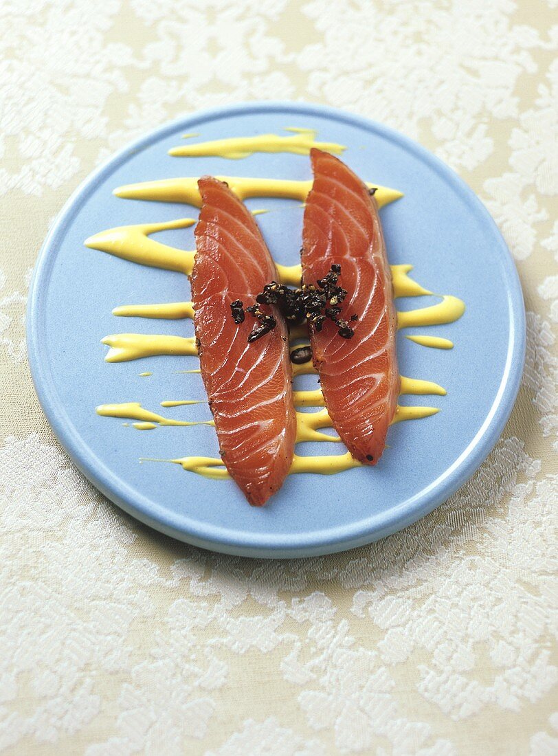 Two slices of salmon marinated in coffee with saffron sauce 