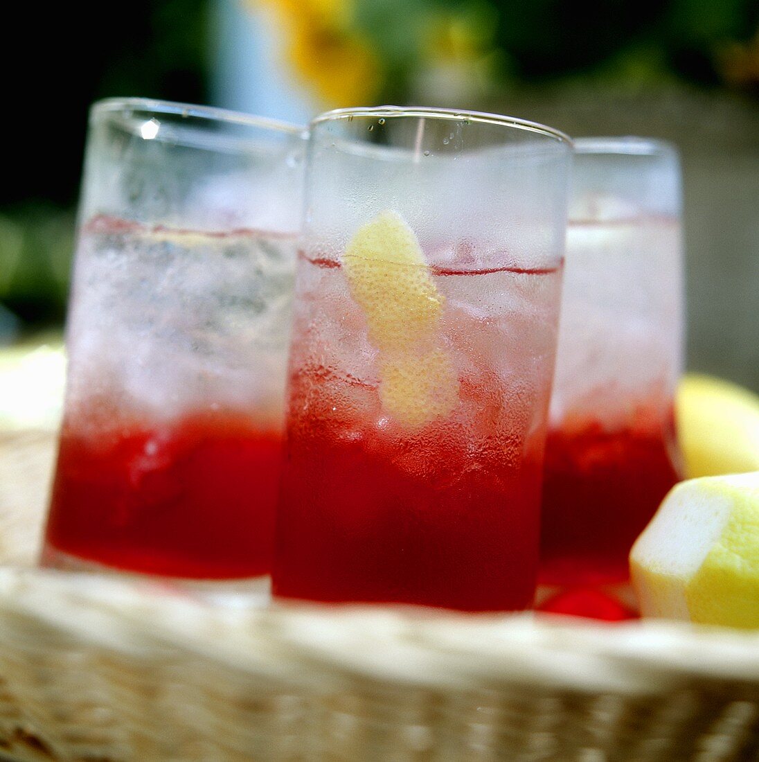 Several glasses of Campari with ice & lemon on wicker tray