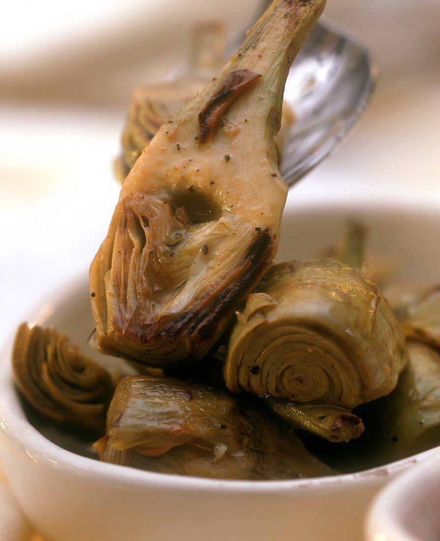 Marinated artichokes in dish & on serving spoon