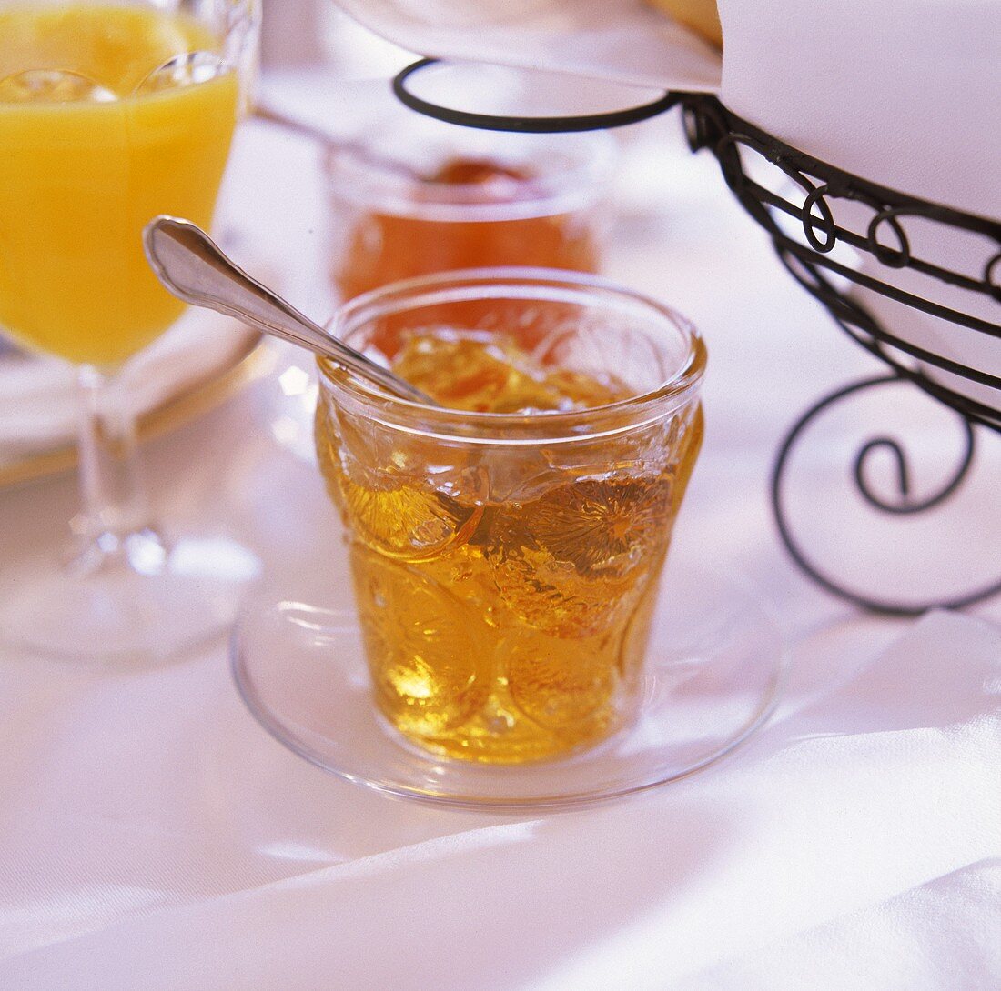 Ein Glas selbstgemachte Orangenmarmelade auf Frühstückstisch