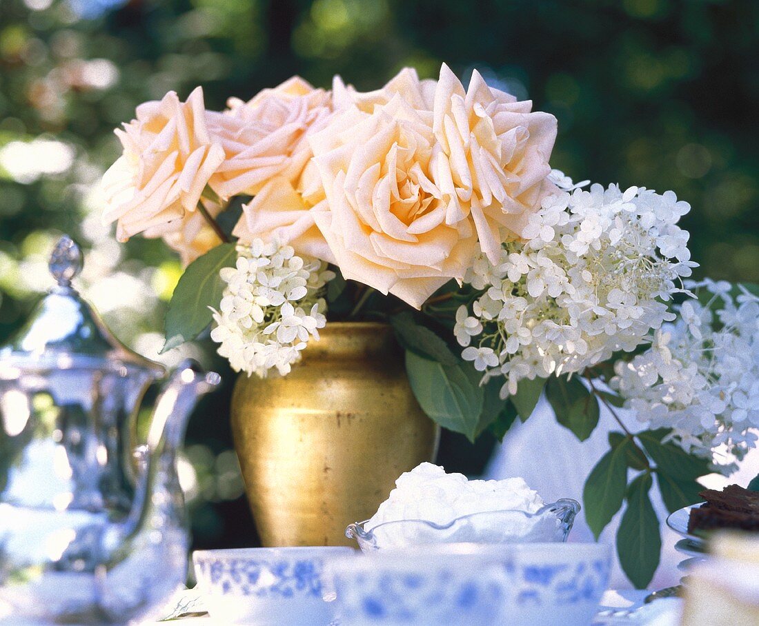 Vase mit lachsfarbenen Rosen & weissen Blüten auf Kaffeetisch