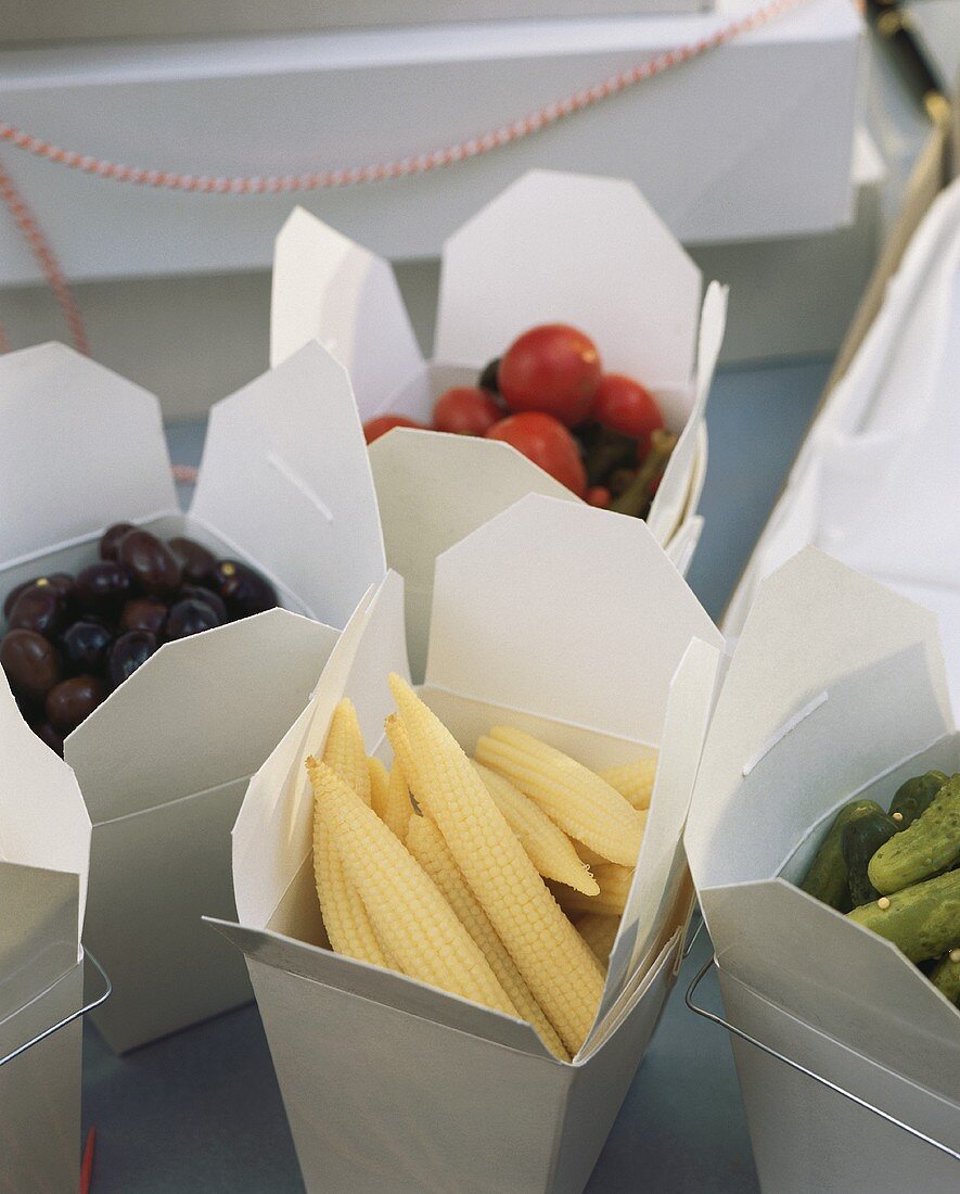 Olives, corncobs and gherkins in boxes