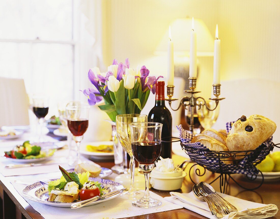 Gedeckter Tisch mit Tulpenstrauss, Vorspeisen, Brot & Rotwein