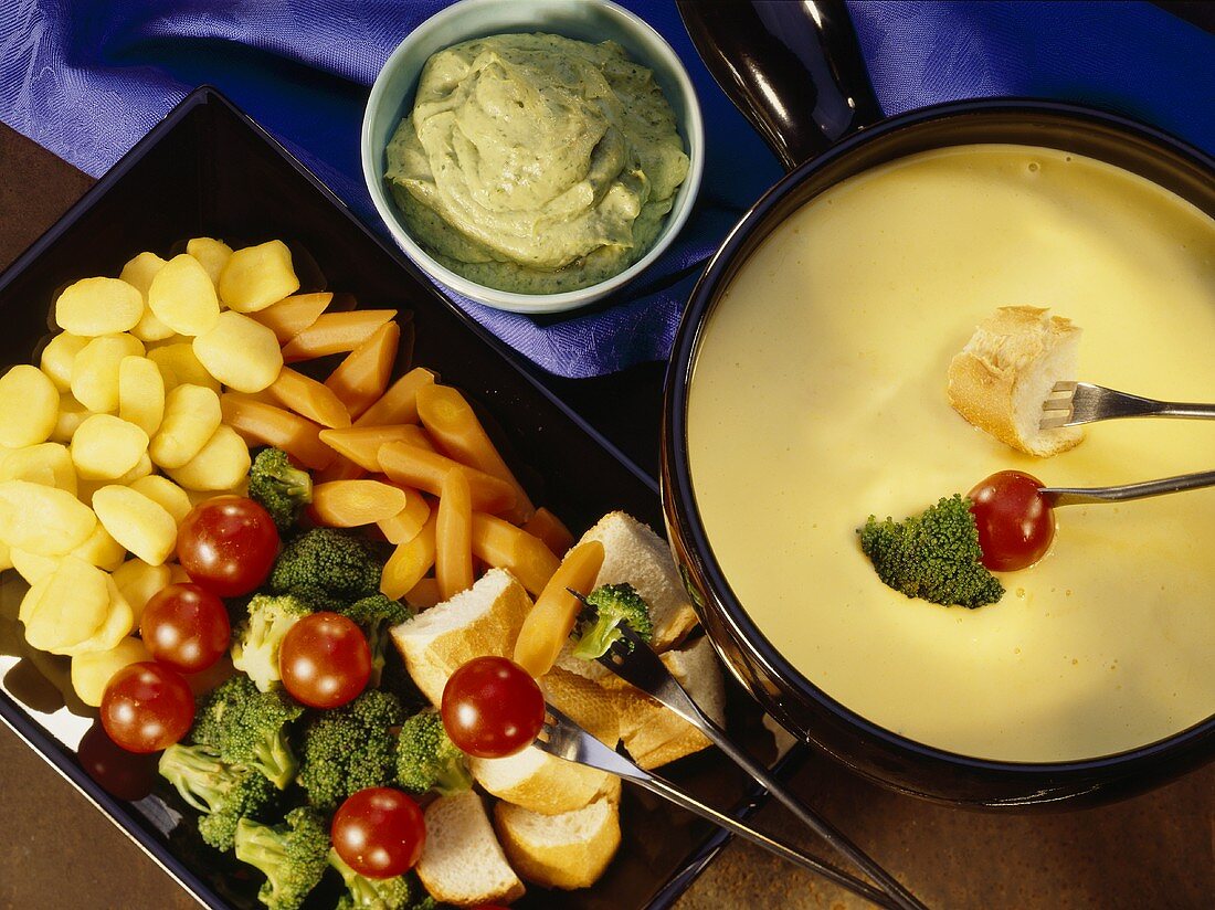 Cheese fondue with parsley & avocado dip, vegetables, bread