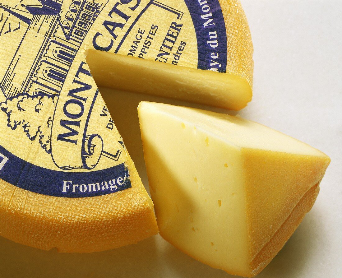 French Trappist cheese with a piece cut out & a piece of cheese