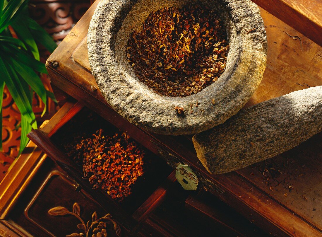 Sichuan peppercorns, whole and ground in stone mortar