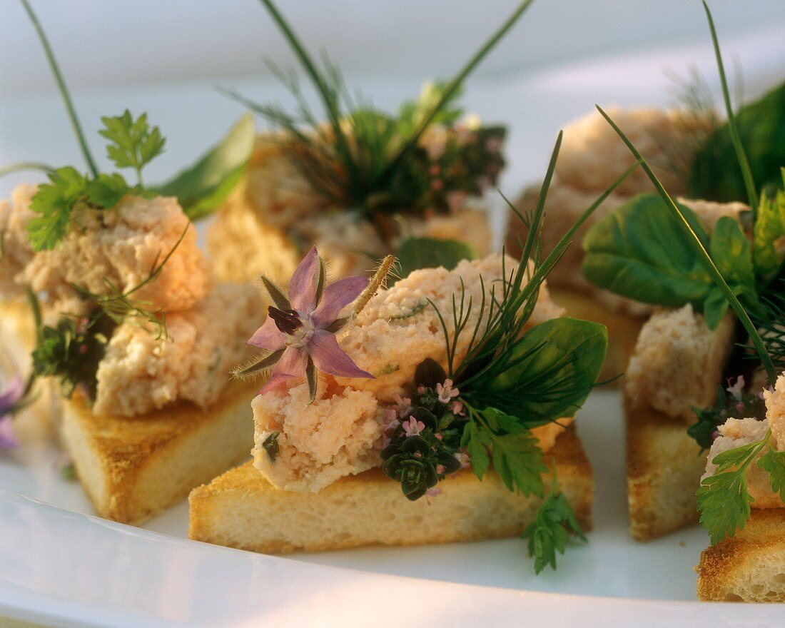 Slices of toast with ham mousse, herbs and flowers