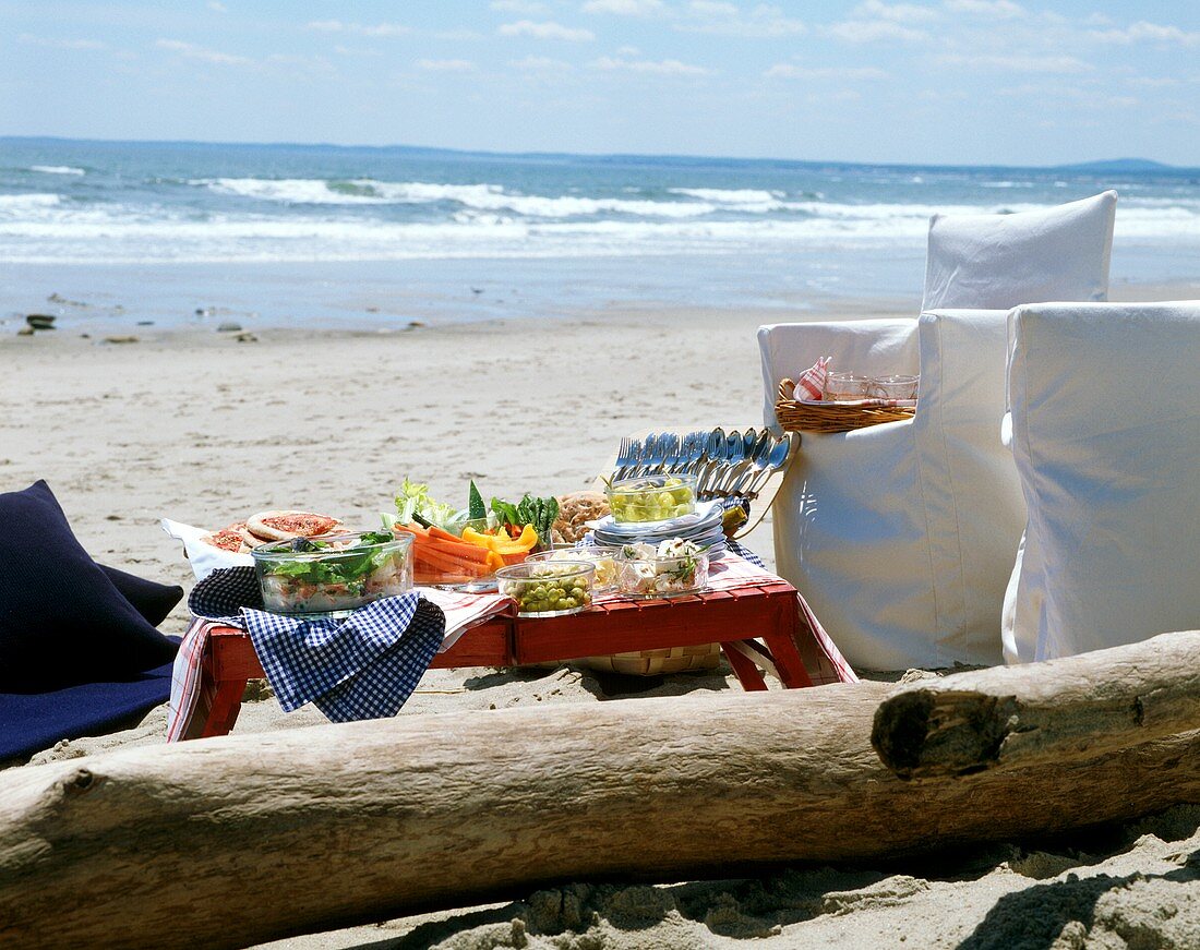 Picknick am Meer: gedeckter Tisch, weiße Stühle, Besteck