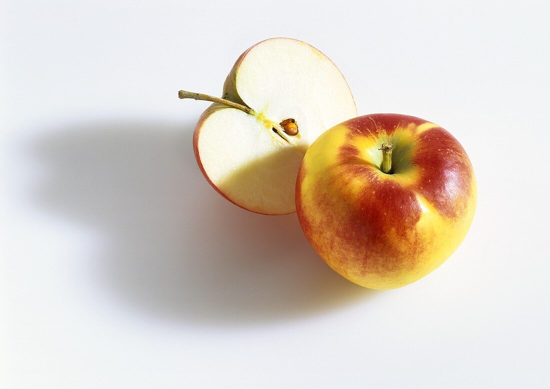 Whole and half a red and yellow apple