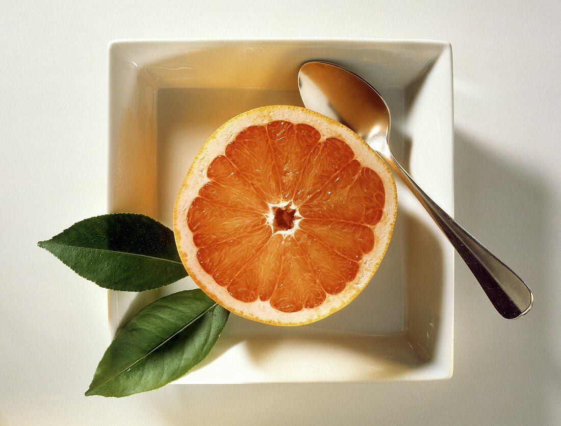 Half of a Pink Grapefruit with a Spoon in a Square Plate