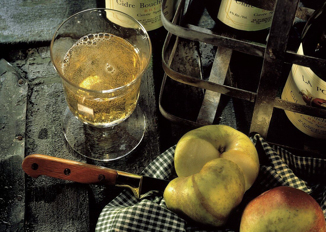 Glas mit perlendem Cidre, Äpfel & Cidre-Flaschen
