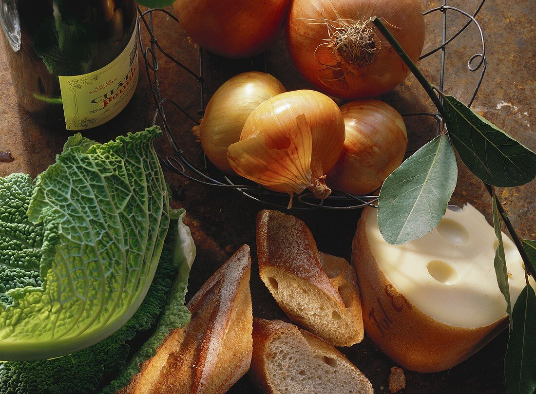 Stillleben mit Zwiebeln, Wirsingblättern, Baguette & Käse