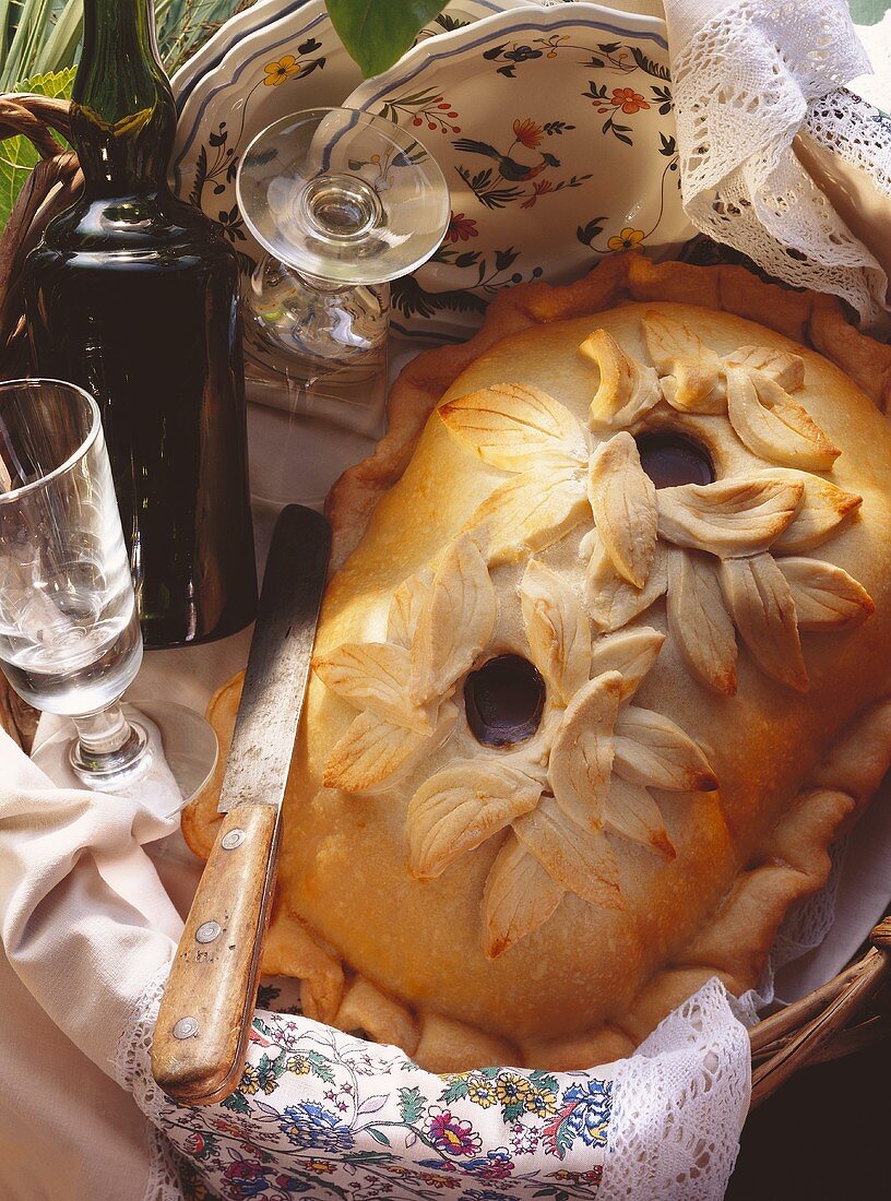 Duck pie with pastry leaf decoration on wicker tray