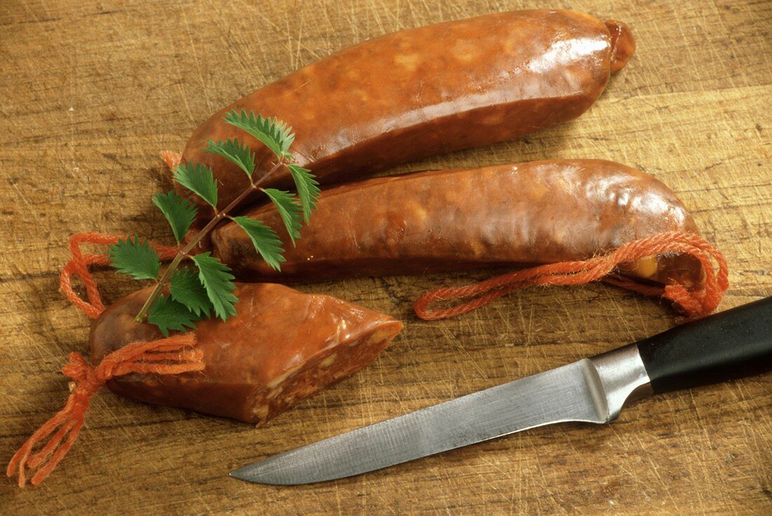 Chorizo-Würste, eine davon angeschnitten, auf Holzbrett