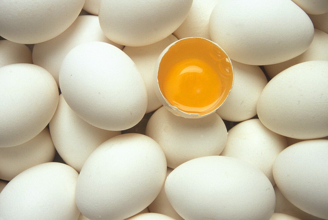 Viele weiße Eier, darunter ein aufgeschlagenes Ei