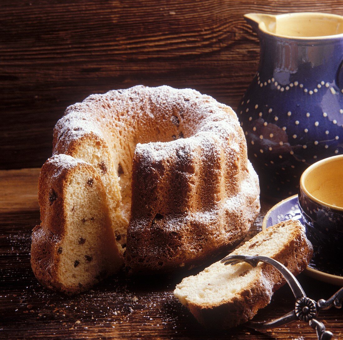 Gugelhupf with raisins & icing sugar on wooden background