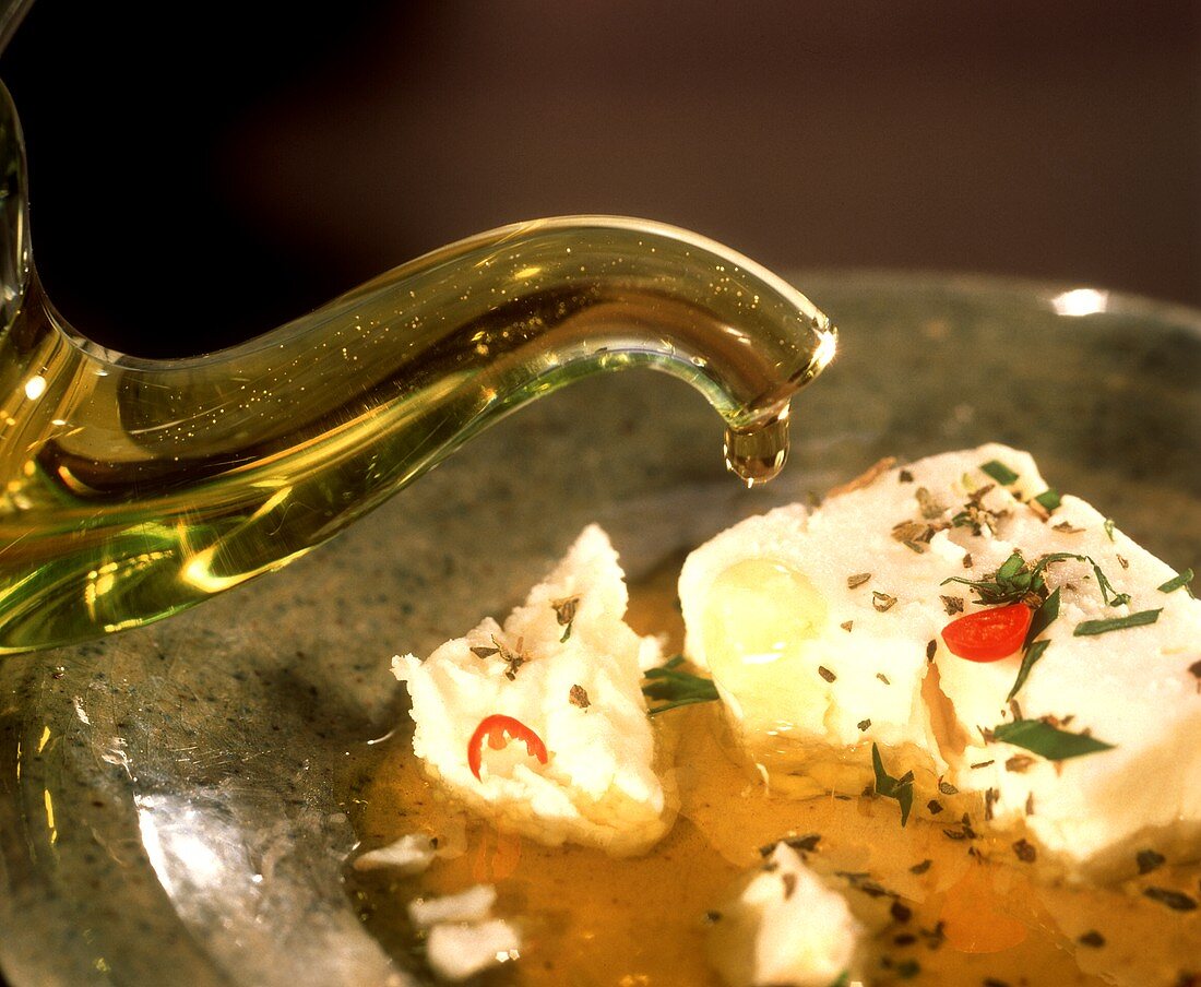 Schafskäse wird mit Olivenöl, Kräutern & Gewürzen mariniert