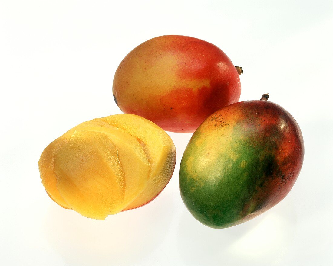 Zwei ganze Mangos & eine angeschnittene geschälte Mango