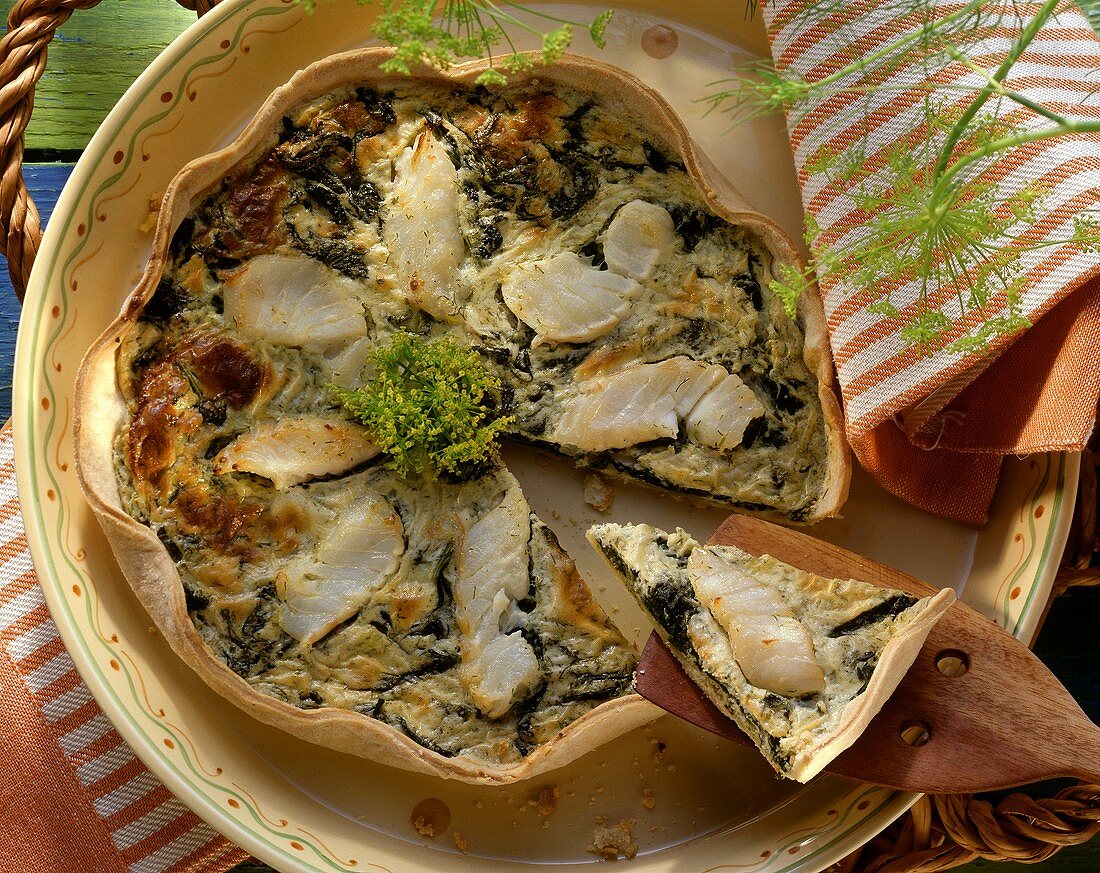 Kabeljauquiche mit Dillcreme, Dillblüten, ein Stück angehoben