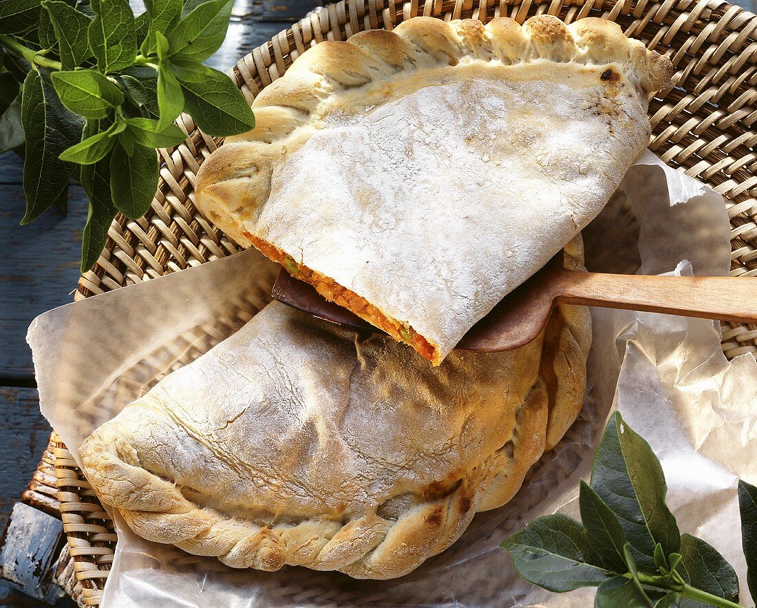 Calzone with ham and mozzarella filling on paper in basket