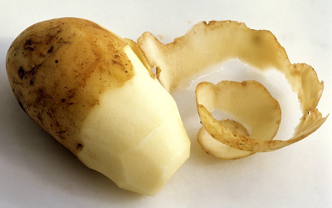 Eine halb geschälte rohe Kartoffel