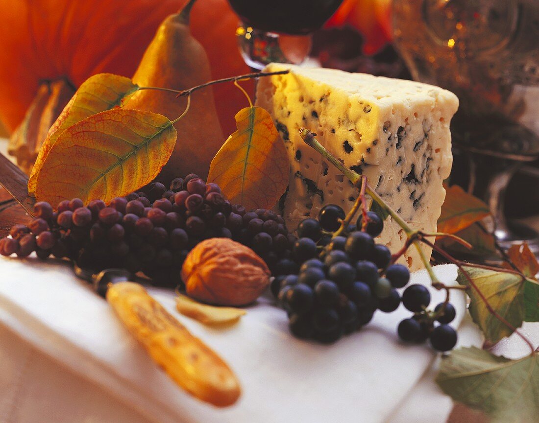 Ein Stück Blauschimmelkäse mit roten Trauben, Birne, Rotwein