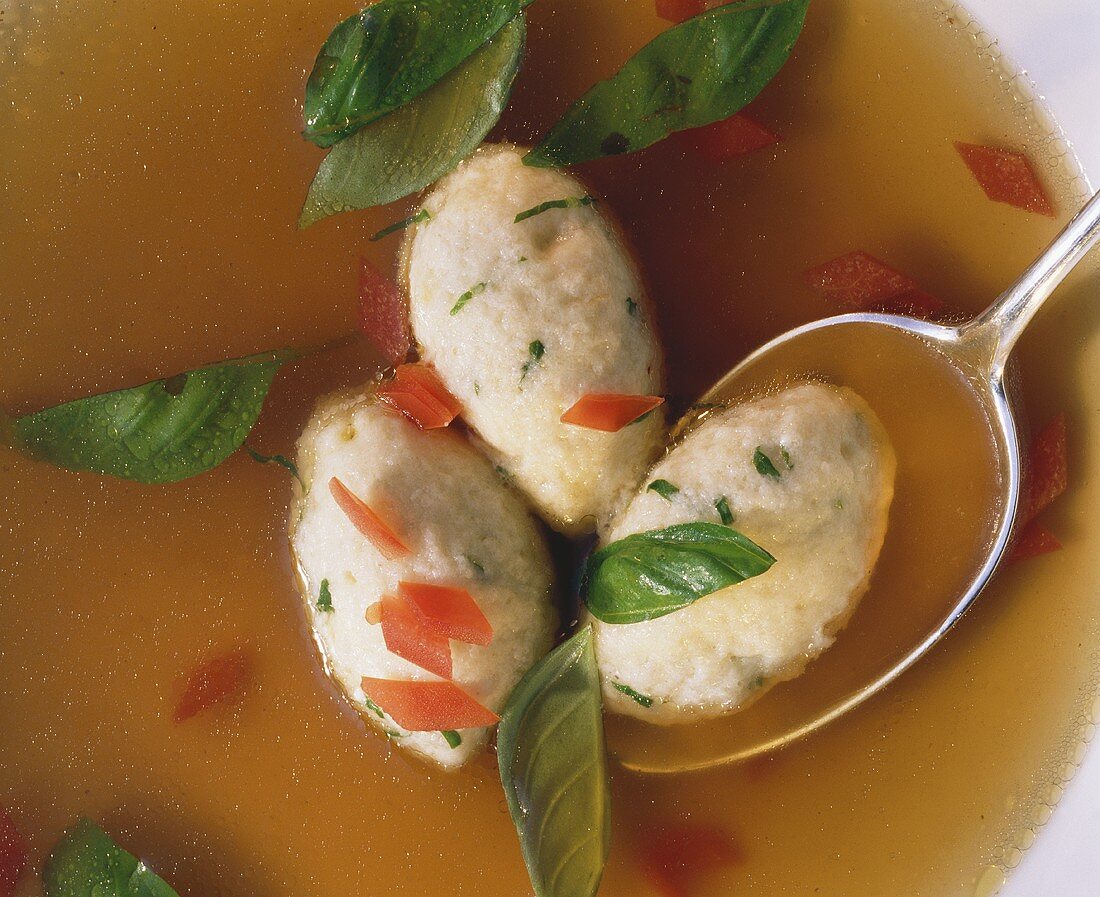 Quark and basil dumpling with spoon in clear broth