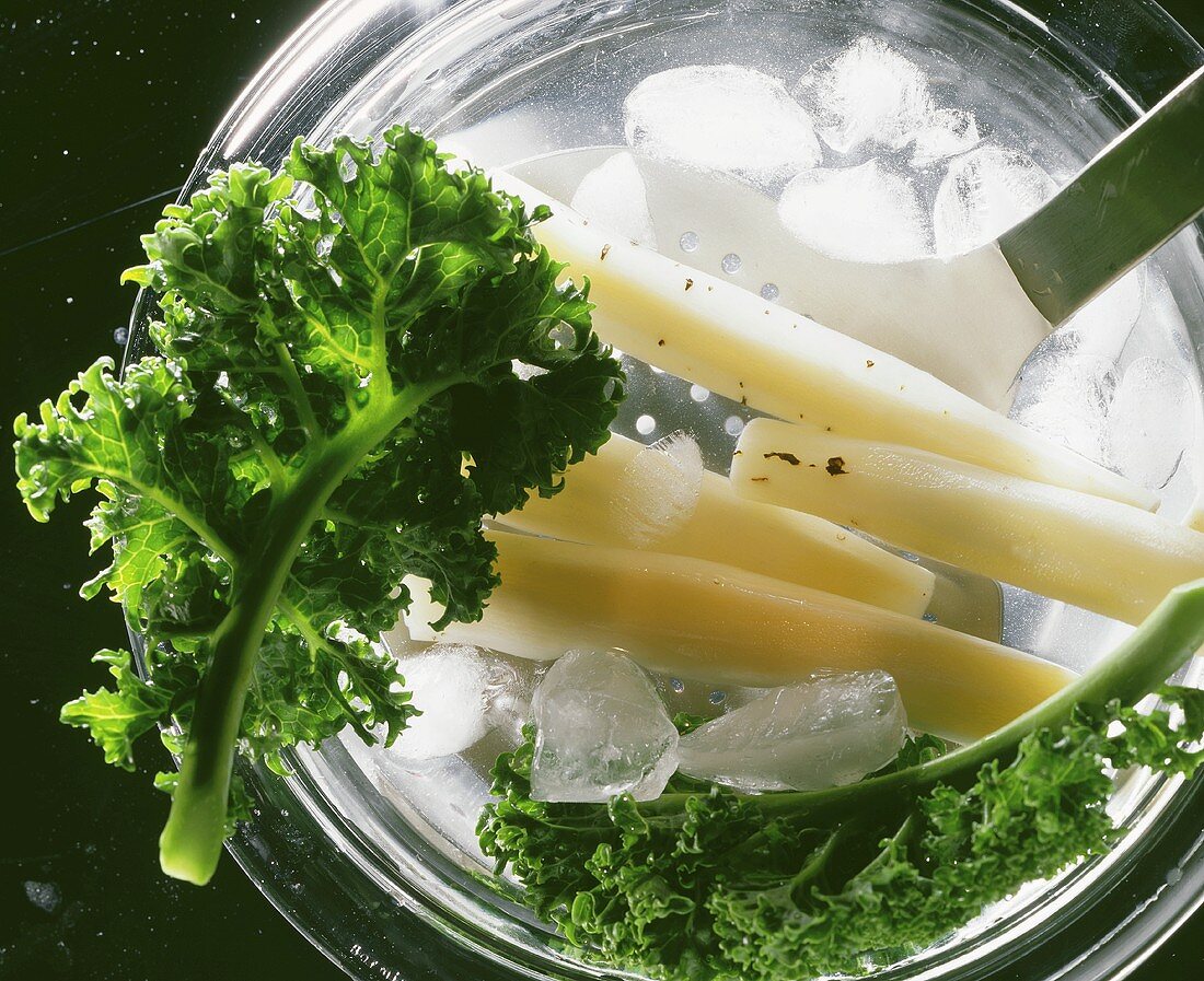 Scorzonera and kale on slotted spoon in iced water