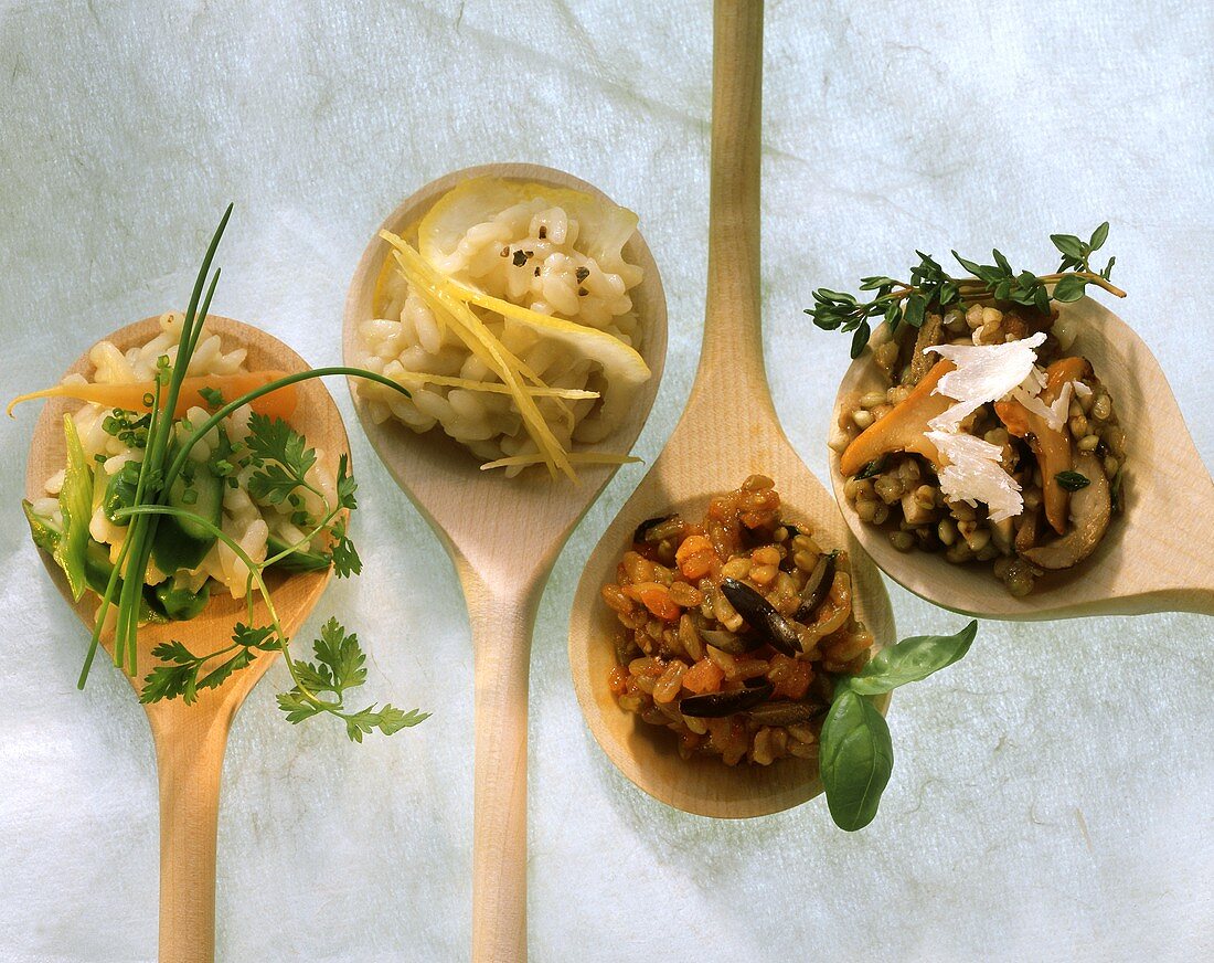 Mehrere verschiedene Risotto-Gerichte auf Holzkochlöffeln