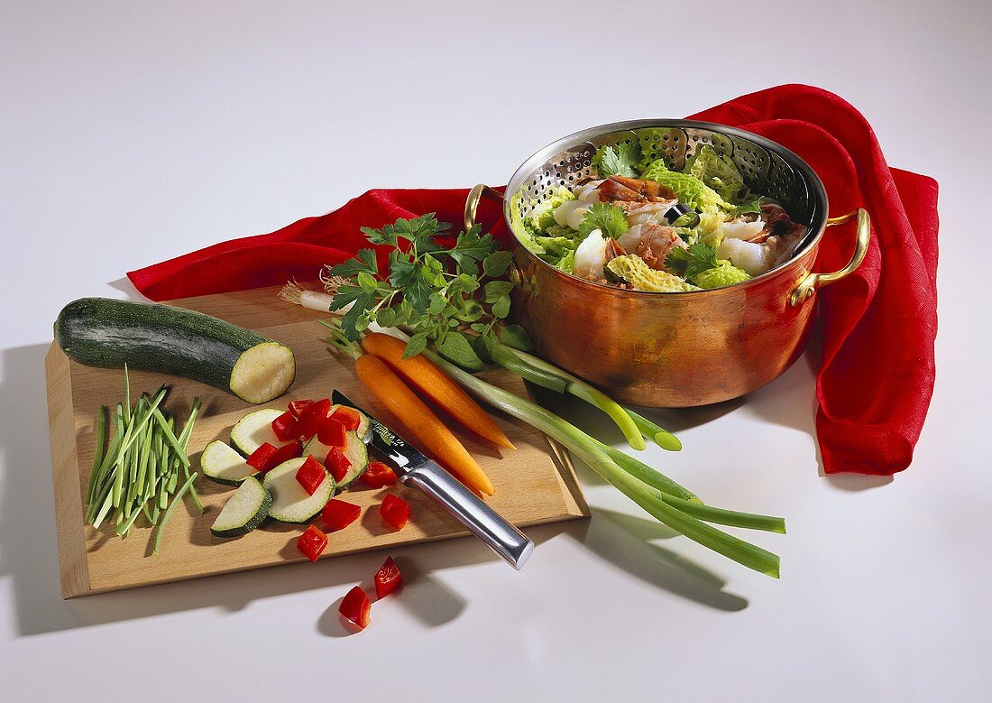 Vegetables on chopping board & in pan with strainer insert