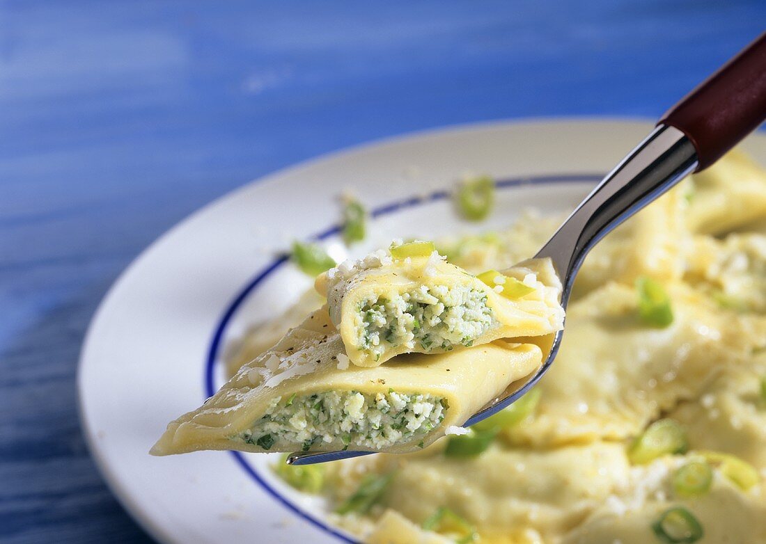 Ricotta ravioli with basil on fork over plate
