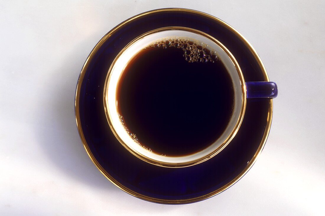 Schwarzer Kaffee in dunkelblauer Tasse mit Goldrand