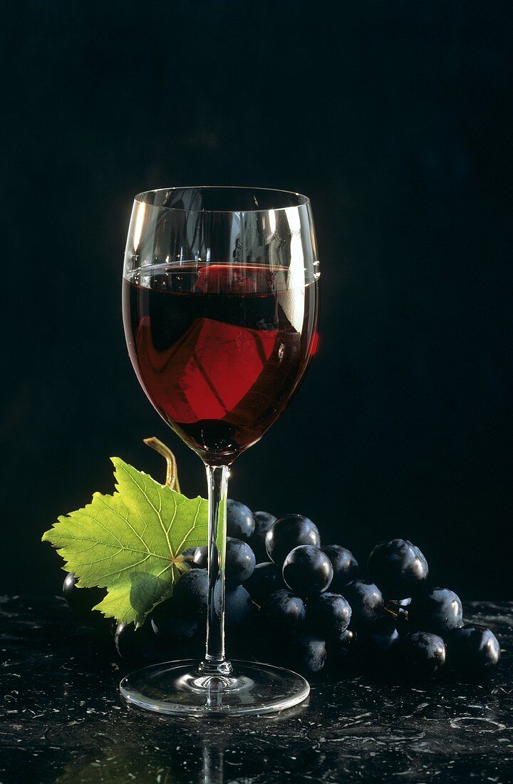 A glass of red wine and red grapes