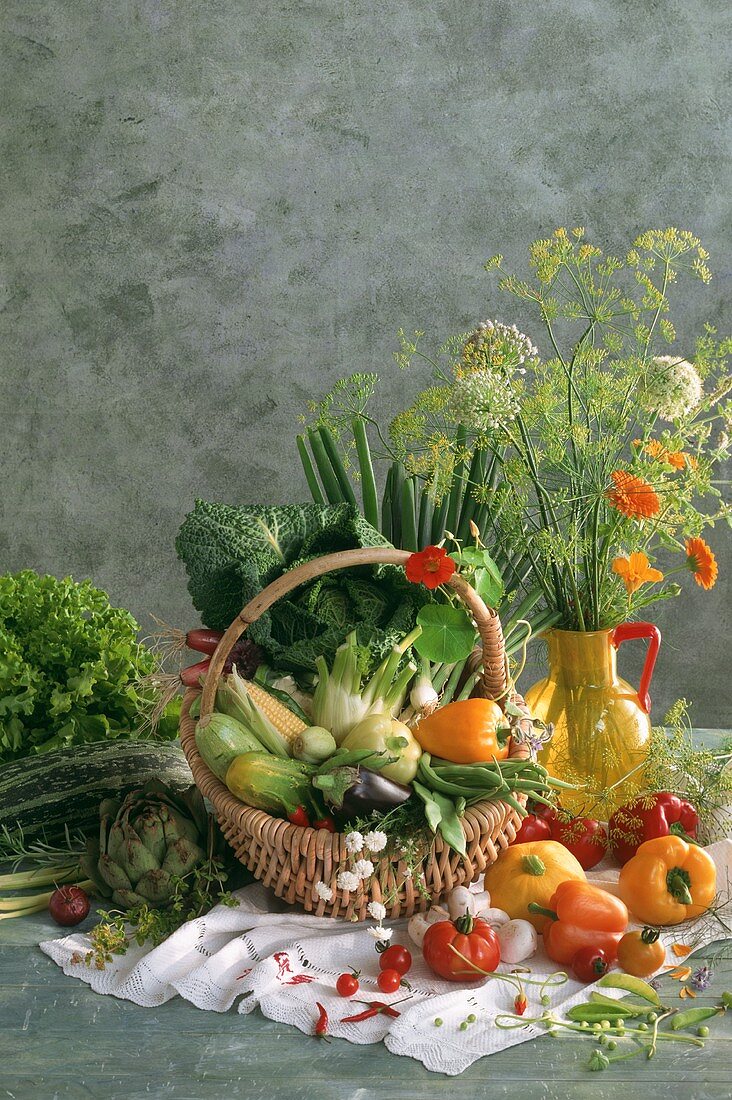 Vegetables in a basket and flowering herbs in vase