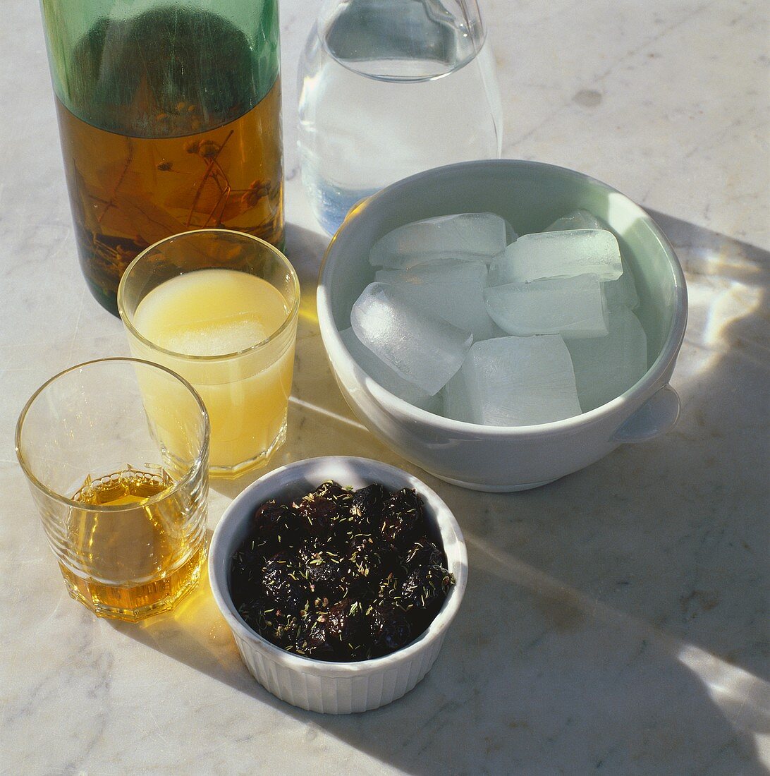 Kräuterschnaps & Wasserflasche, Eiswürfel & schwarze Oliven