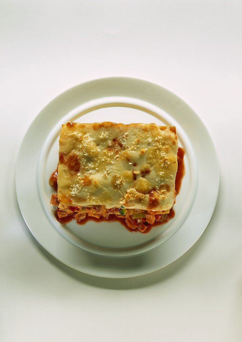 Ein Stück Lasagne auf einem weissen Teller